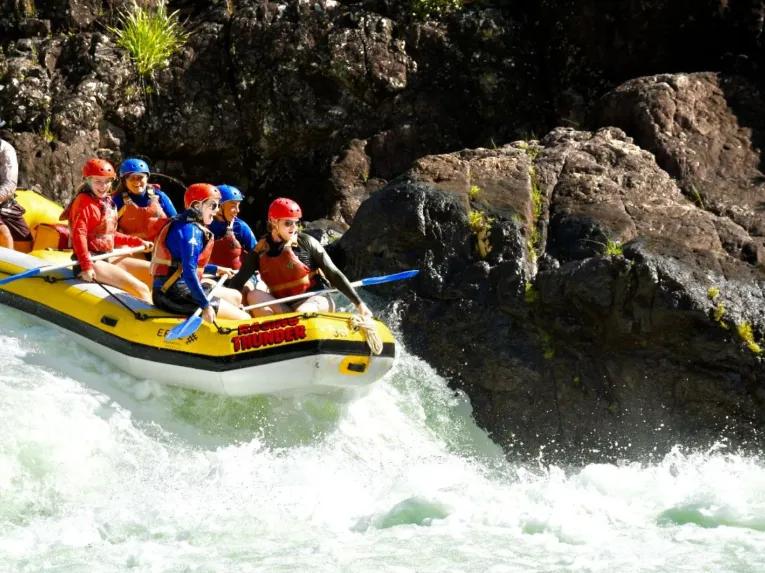 A raft full of people navigating a small drop on the Barron River during white water rafting