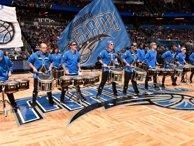 Drumline performing with big flags on the court at an Orlando Magic game