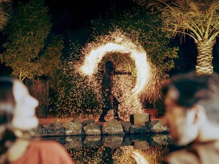 Couple watching a fire dancer perform at a desert camp at night