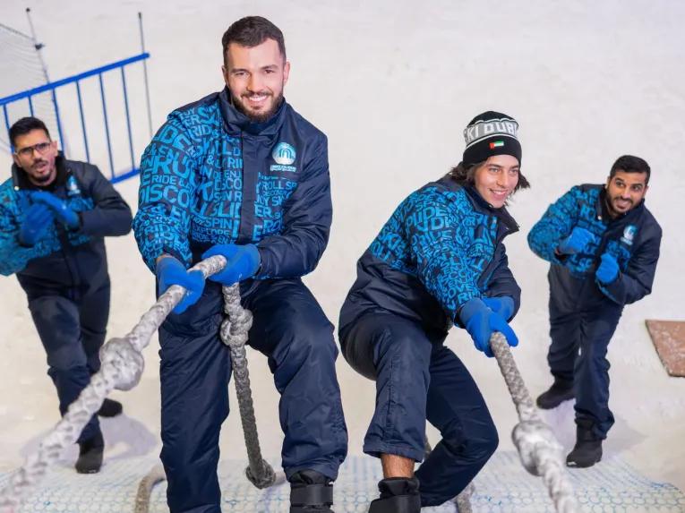 Group of visitors wearing winter gear enjoying Ski Dubai’s indoor snow park.