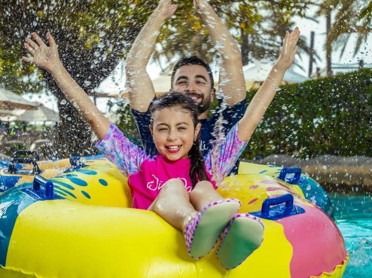 Family smiling and having fun in the water at Wild Wadi Waterpark