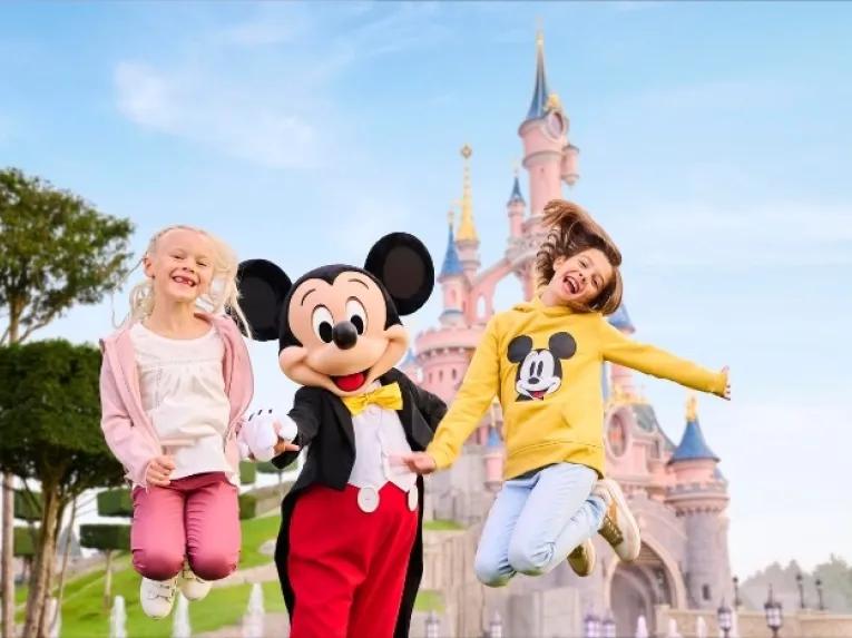 Mickey Mouse jumps in the air with 2 girls
