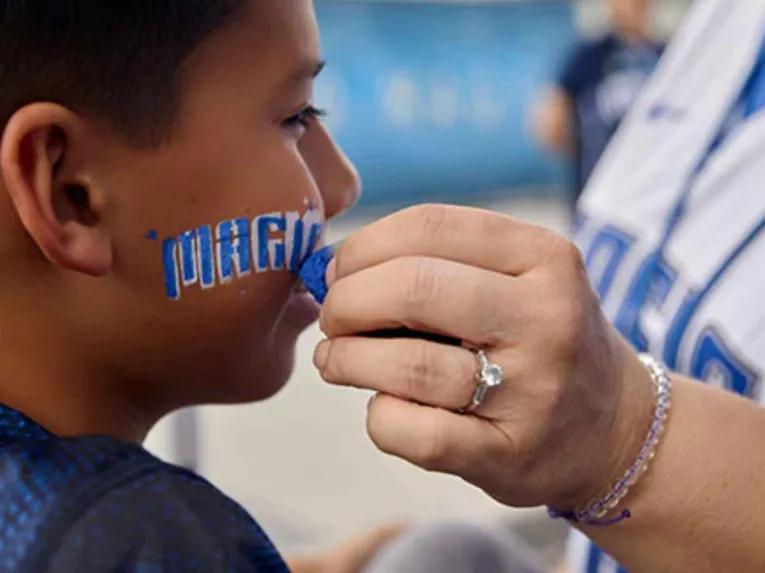 Young fan receiving blue and white Orlando Magic face paint